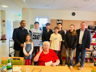 Eine Gruppe von sieben Kindern und Erwachsenen posiert mit einer älteren Frau.