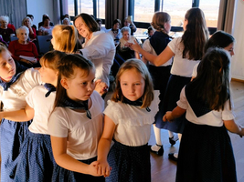 Kinder führen einen Tanz auf, während ältere Zuschauer zuschauen.