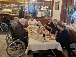 Gruppe von Personen in Rollstühlen, die gemeinsam in einem Restaurant essen.