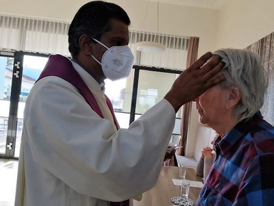 Ein Priester spendet einer älteren Frau den Segen.