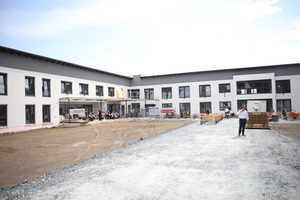 Neubau eines Gebäudes mit Menschen und Baustellenmaterial im Vordergrund.