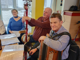 Eine Gruppe von Menschen sitzt zusammen und spielt Musik mit Instrumenten.