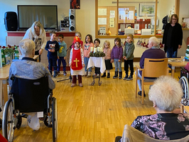 Kinder führen ein Stück für ältere Menschen in einem Gemeinschaftsraum auf.