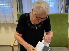 Eine ältere Frau reibt einen Apfel mit einer Küchenreibe in eine Schüssel.
