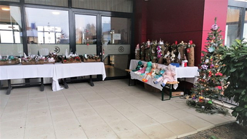 Weihnachtliche Dekorationen und Bastelarbeiten auf Tischen vor einem Gebäude.