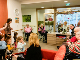 Kinder und Senioren interagieren in einem Gemeinschaftsraum, Musik macht Freude.