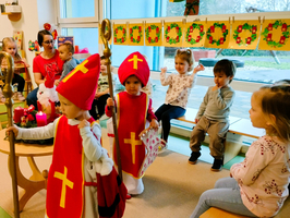 Kinder in Kostümen feiern eine festliche Veranstaltung in einem Klassenraum.