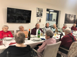 Eine Gruppe älterer Menschen sitzt beim gemeinsamen Essen an einem Tisch.
