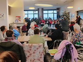 Kinder stehen auf der Bühne und singen vor einem Publikum in einem Saal.