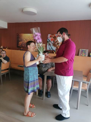 Eine Frau erhält einen Blumenstrauß von einem Mann in einem Pflegeheim.