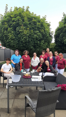 Eine Gruppe von Personen in Arbeitskleidung steht um einen Tisch im Freien.