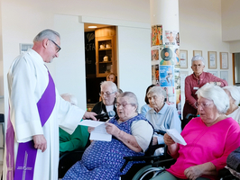 Ein Priester spricht mit Senioren in einem Gemeinschaftsraum.