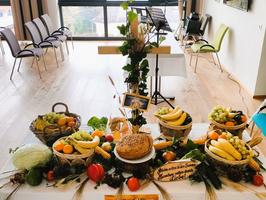 Tisch mit Obst, Gemüse und einem Brot, dekoriert für eine Feier.