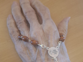 Eine Hand mit einem Holz- und Perlenrosenkranz.
