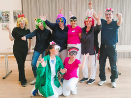 Gruppe von Menschen in bunten Kostümen und Hüten, die fröhlich posieren.