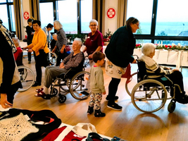 Gruppenausflug mit Senioren in Rollstühlen, begleitet von einem Kind in einem Raum.