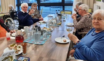 Eine Gruppe älterer Menschen sitzt an einem Tisch und feiert mit Getränken.