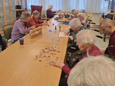 Ältere Menschen arbeiten gemeinsam an einem Tisch mit Buchstaben und Spielen.