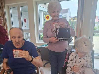 Drei Personen in einem Raum halten Bingo-Karten und haben Spaß.