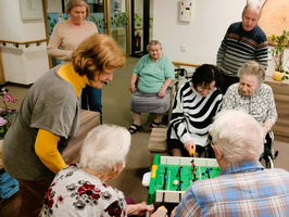Senioren spielen gemeinsam Tischfußball in einem Aufenthaltsraum.