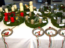Weihnachtliche Kränze mit Kerzen und dekorativen Elementen auf einem Tisch.