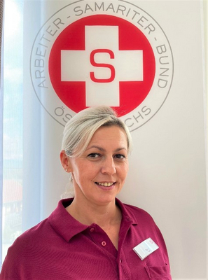 Frau in rotem Polo-Shirt vor einem Samaritern-Logo.