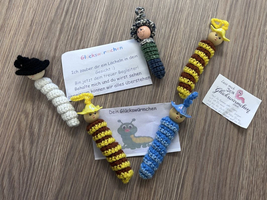 Fünf handgefertigte Glückswürmer aus Wolle mit bunter Gestaltung.