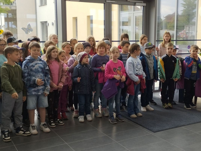 Eine Gruppe von Kindern steht in einem Eingangsbereich und lächelt.