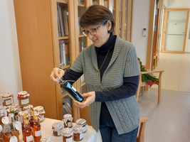 Eine Frau betrachtet ein Glas Marmelade auf einem Tisch.