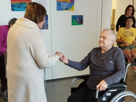 Eine Frau reicht einem Mann im Rollstuhl die Hand.