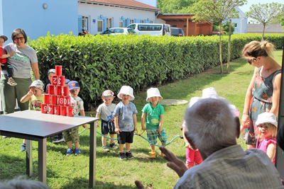 Kinder stehen in einer Reihe vor einem aufgestellten Turm aus roten Bechern.