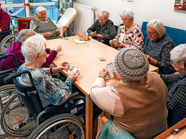 Eine Gruppe älterer Frauen spielt gemeinsam Karten in einem Gemeinschaftsraum.