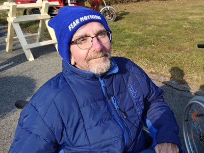 Zwei ältere Männer sitzen im Freien, einer schaut in die Sonne.