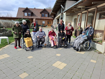 Einige ältere Menschen in Rollstühlen stehen zusammen im Freien.