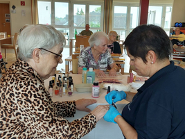 Seniorinnen genießen eine Nagelpflege in einem Gemeinschaftsraum.