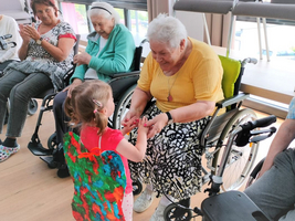 Ein kleines Mädchen hält die Hand einer älteren Dame in einem Pflegeheim.