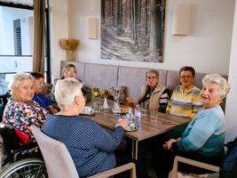 Eine Gruppe älterer Frauen sitzt gemeinsam an einem Tisch und unterhält sich.