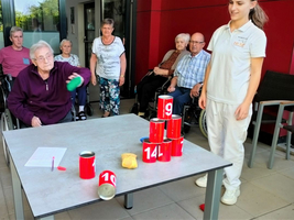 Eine Gruppe älterer Menschen spielt ein Zielwurfspiel mit Dosen.