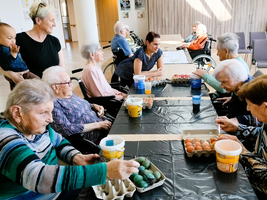 Ältere Menschen und ein Kind färben gemeinsam Eier an einem Tisch.