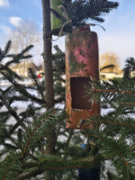 Bunte Futterstelle aus einer Flasche, aufgehängt an einem Weihnachtsbaum.