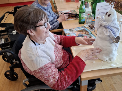 Eine Frau im Rollstuhl präsentiert einen Schneemann auf einem Tisch.