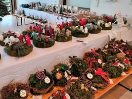 Weihnachtliche Kränze mit Kerzen und Dekoration auf Tischen präsentiert.