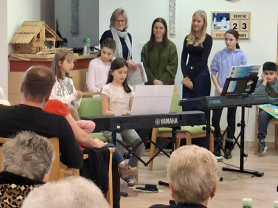 Kinder singen und spielen Klavier bei einer Aufführung vor Publikum.