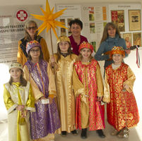 Gruppe von Kindern in festlicher Kleidung mit einem Stern und fröhlichen Gesichtern.