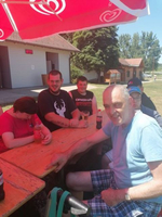 Gruppe von Menschen sitzt am Tisch unter einem roten Sonnenschirm und genießt Getränke.