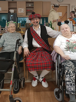 Eine fröhliche Gruppe mit zwei älteren Frauen und einem Mann in traditioneller Kleidung.