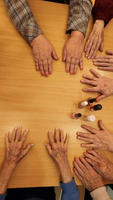 Hände älterer Menschen liegen auf einem Tisch, Nagellackfläschchen sind sichtbar.