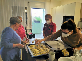 Vier Frauen backen gemeinsam Gebäck in einer hellen Küche.