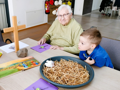 Eine ältere Frau und ein Junge basteln gemeinsam an einem Tisch.