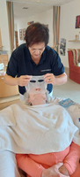 Eine Person legt eine Gesichtsmaske auf eine liegende Frau.